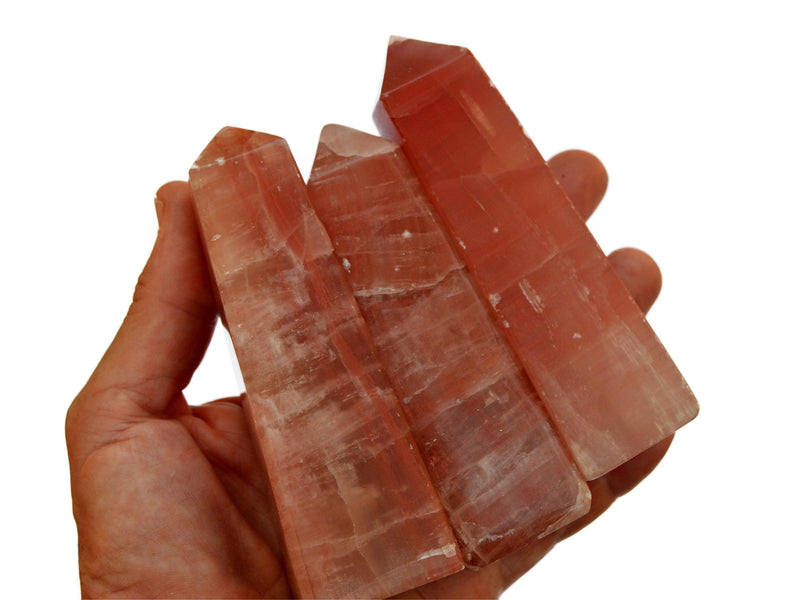 Three large rose calcite obelisks 85mm-90mm on hand with white background