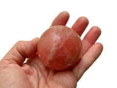 One rose calcite sphere 50mm on hand with white background