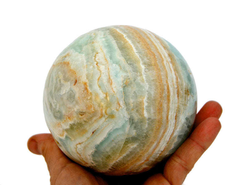 Large caribbean calcite sphere crystal 100mm on hand with white background