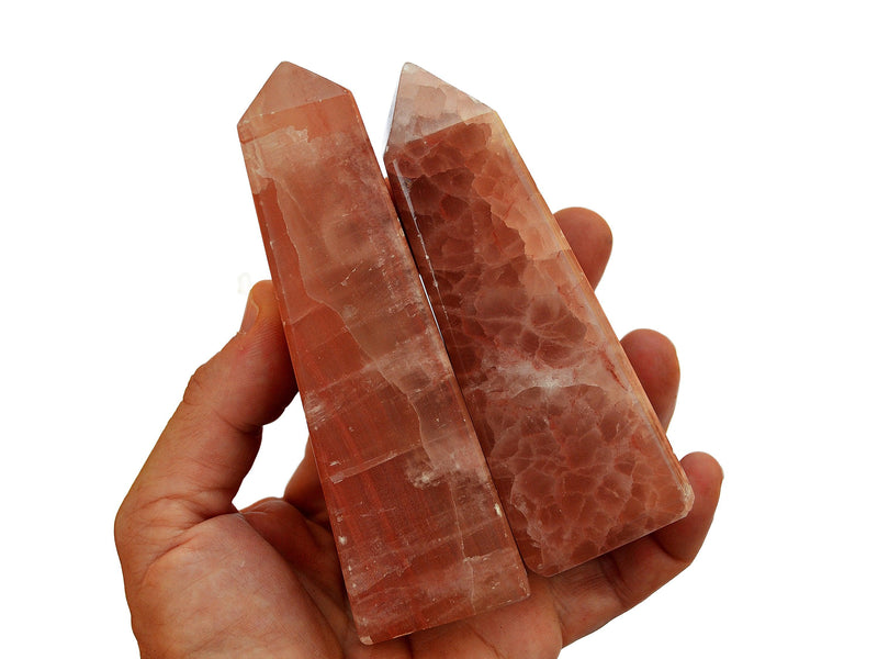 Two pink calcite tower crystals 100mm-110mm on hand with white background