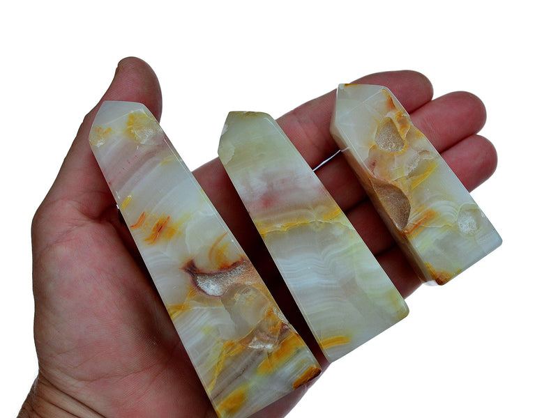 Three pink banded onyx tower crystals 70mm-90mm on hand with white background