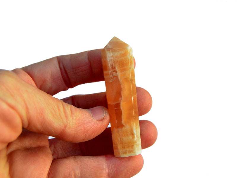 One honey calcite mini crystal tower 55mm on hand with white background