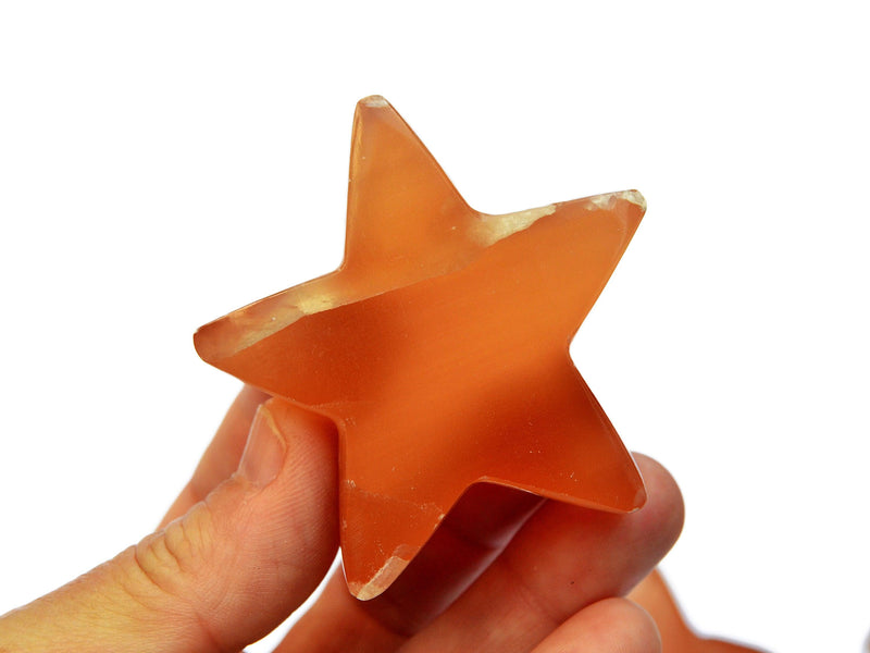 One honey calcite star carving crystal 55mm on hand with white background 