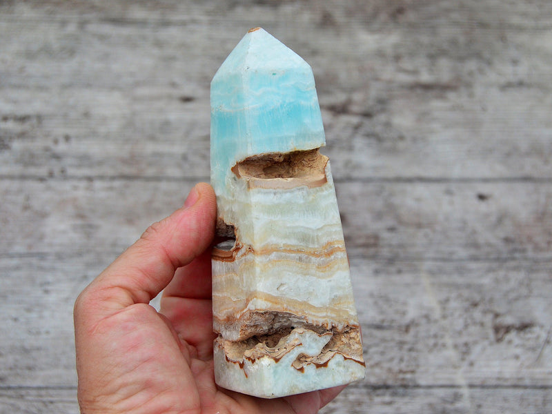 One large and chunky caribbean crystal druzy tower on hand with wood background