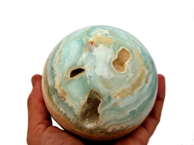 Large caribbean calcite sphere crystal 90mm on hand with white background