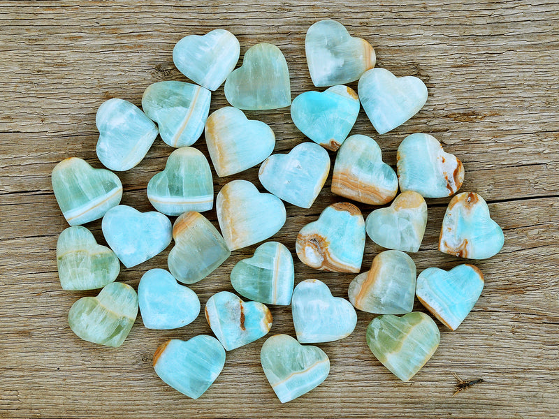 Several blue green caribbean calcite heart shapped crystals 35mm-40mm on wood table
