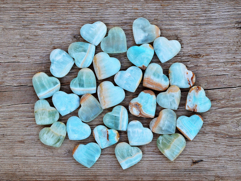 Several blue green caribbean calcite heart shapped crystals on wood table