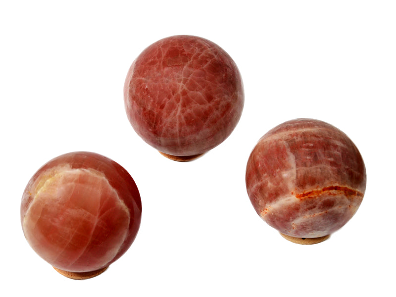 Three large rose calcite sphere crystals on white background