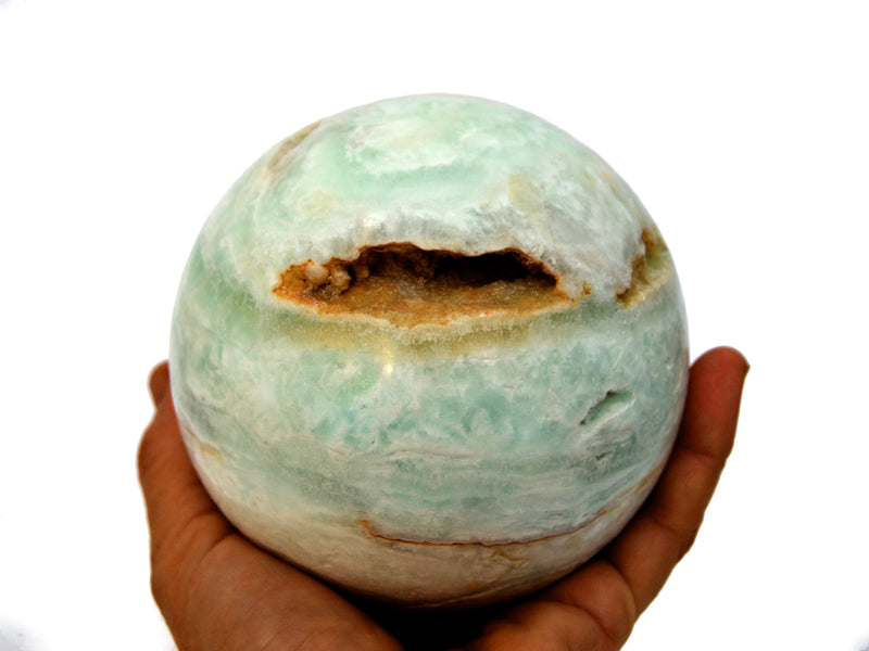 Big caribbean calcite sphere stone 95mm on hand with white background