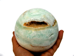 Big caribbean calcite sphere stone 95mm on hand with white background