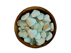 Several blue green caribbean calcite small hearts inside a wood bowl on white background