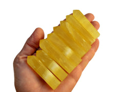 Eight yellow calcite crystal points 50mm-65mm on hand with white background