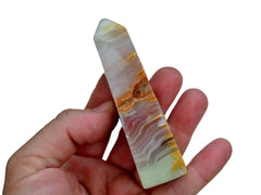 One pink banded onyx tower 80mm on hand with white background