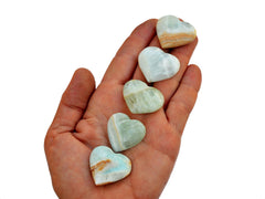 Five blue green caribbean calcite crystal hearts 25mm-30mm on hand with white background