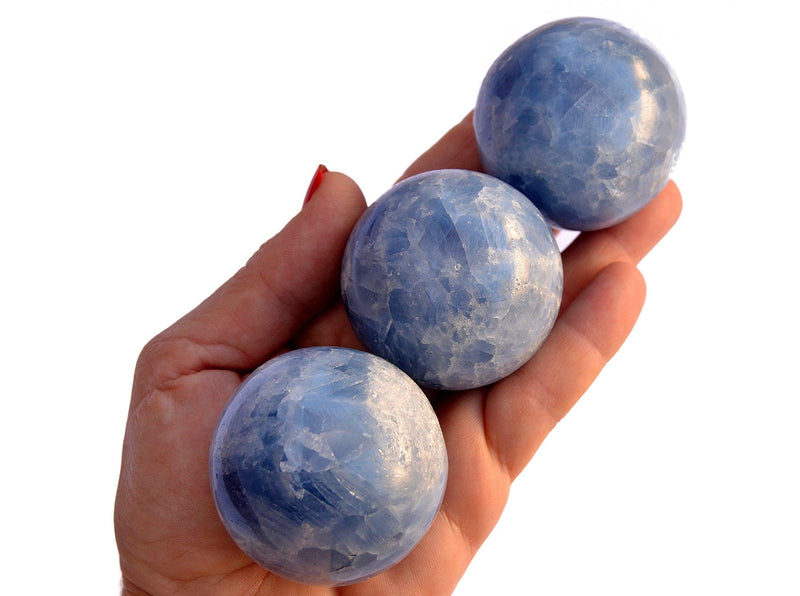Three blue calcite crystal balls 45mm-50mm on hand with white background