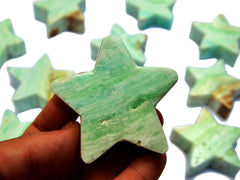 Three blue caribbean calcite star mineral 60mm on hand with background with some stars on white