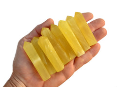 Some lemon calcite crystal points 50mm-65mm on hand with white background