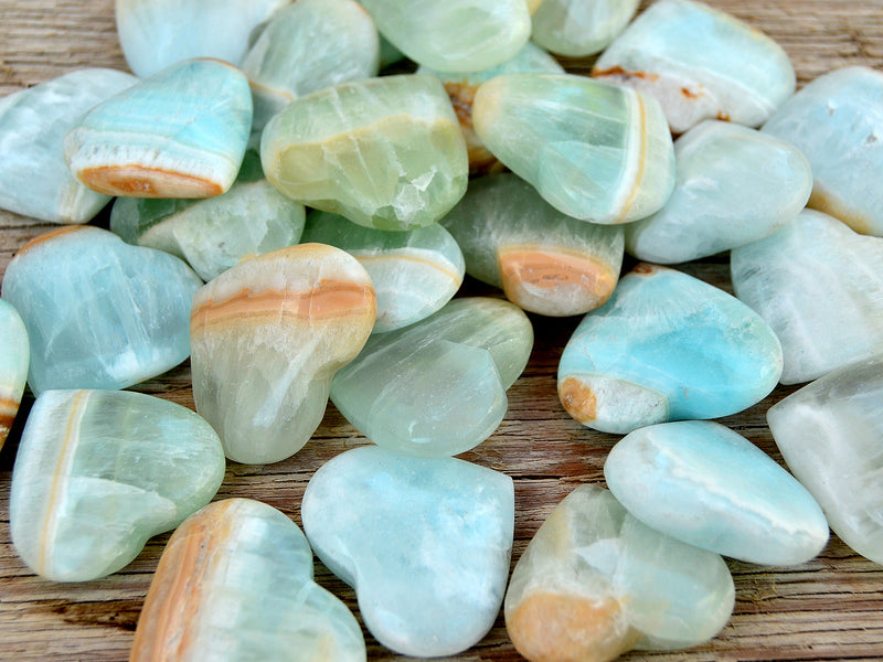 Some caribbean calcite heart crystals 35mm-40mm on wood table