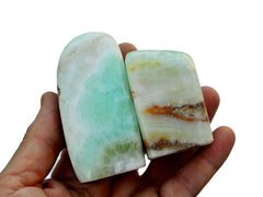 Two aqua blue green caribbean calcite free form crystals on hand with white background