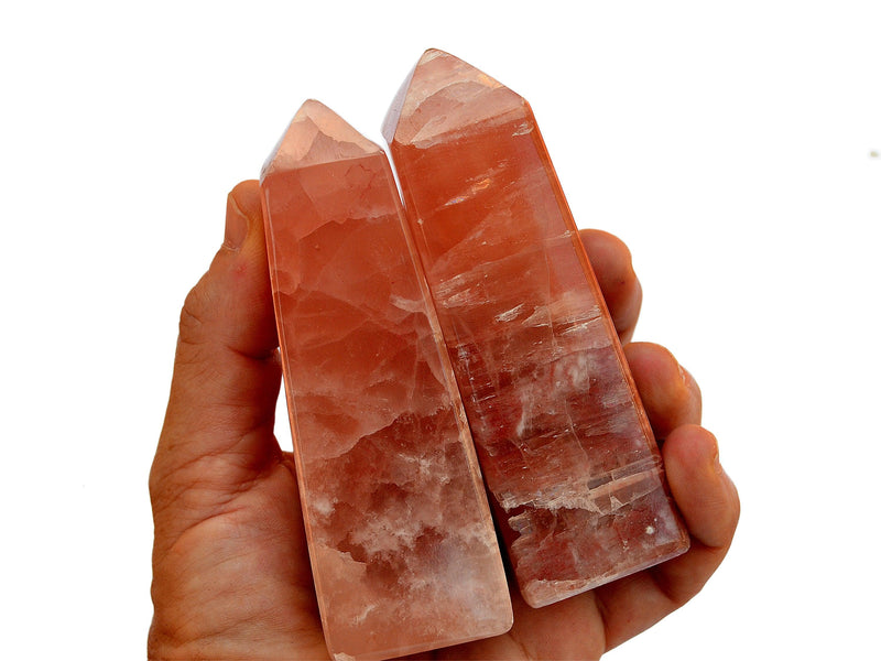 Two pink calcite towers 90mm on hand with white background