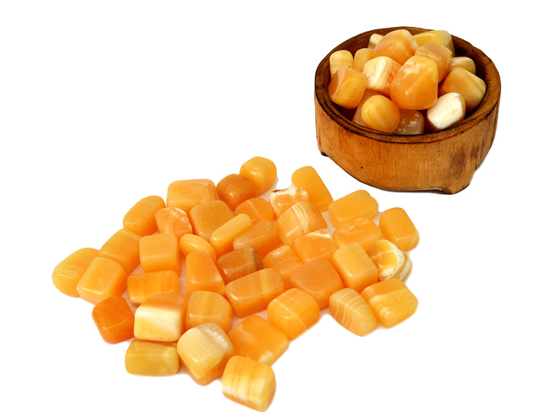 Some orange calcite tumbled minerals inside a wood bowl and some specimens arround on white background