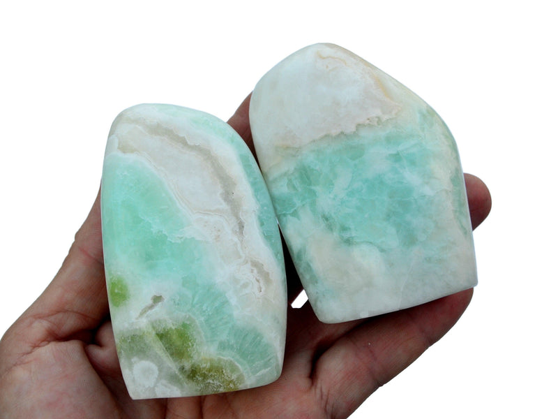Two aqua blue caribbean calcite free form crystals on hand with white background
