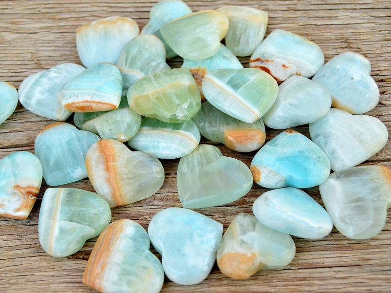 Some blue green caribbean calcite heart shapped crystals on wood table