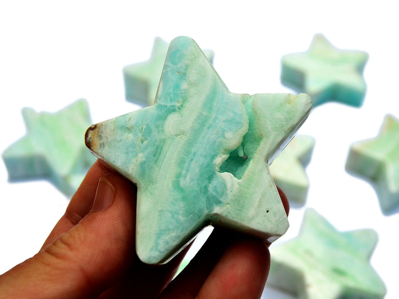 Two blue caribbean calcite star crystal 60mm on hand with background with some stars on white