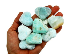 Ten small blue green caribbean calcite crystal hearts 35mm-40mm on hand with white background