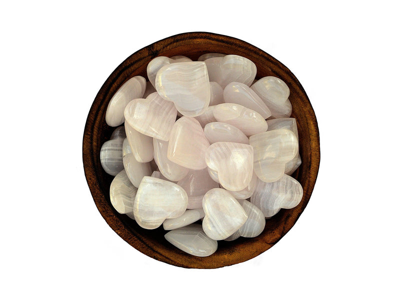 Several small pink mangano calcite heart minerals inside a wood bowl on white background