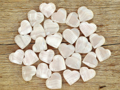 Several small pink mangano calcite heart shapped crystals 30mm-35mm on wood table