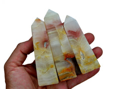 Three pink banded onyx tower crystals 90mm on hand with white background