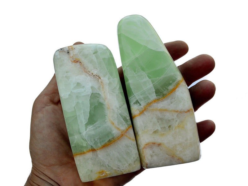 Two green aqua caribbean calcite free form crystals on hand with white background