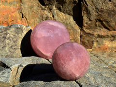 Two large rose quartz crystal spheres 80mm-90mm on natural rock