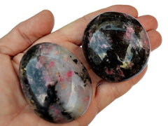Two big rhodonite palm stones on hand with white background