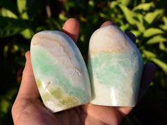 Two aqua blue green caribbean calcite slabs on hand with background with green plants