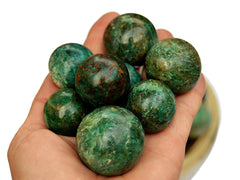 Several green chrysocolla sphere stones 25mm - 40mm on hand with white background