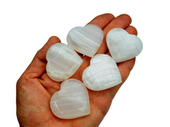 Five pink mangano calcite hearts 35mm-40mm on hand with white background