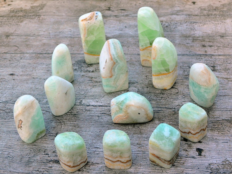 Several blue green caribbean calcite slabs diferrent sizes on wood table
