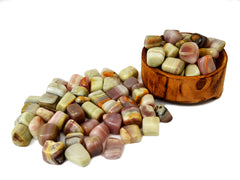 Some pink banded onyx tumbled stones inside a wood bowl and some crystals outside arround