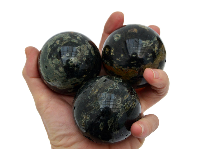 Three green ocean jasper crystal spheres 55mm on hand with white background