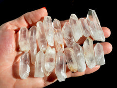 Several raw crystal points on hand with black background