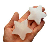 Two pink mangano calcite stars 60mm on hand with white background