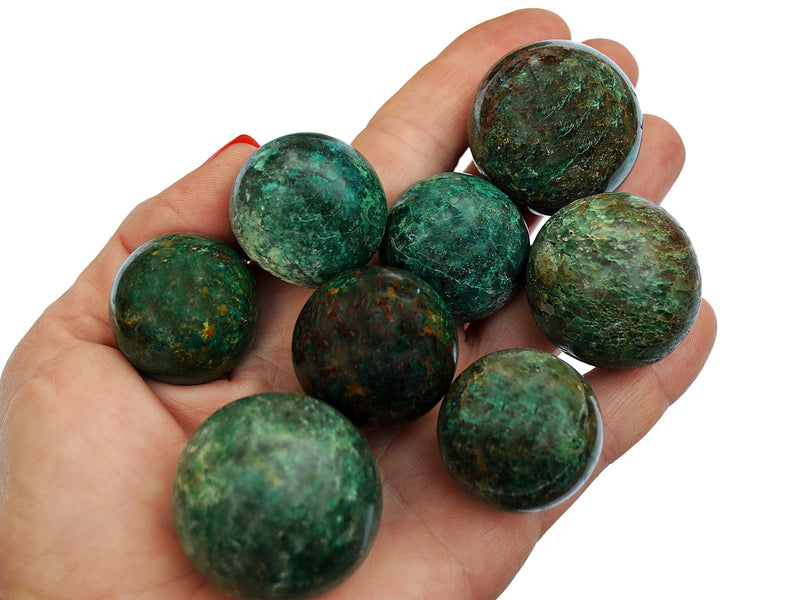 Several green chrysocolla sphere stones 25mm - 35mm on hand with white background