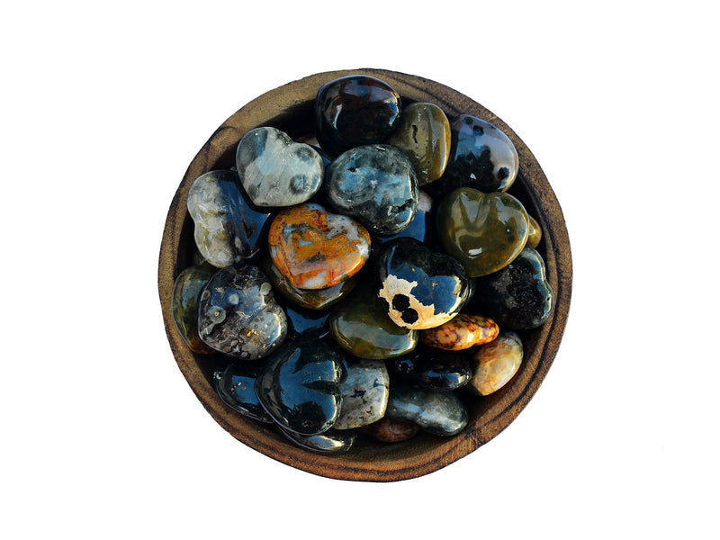 Several ocean jasper heart stones 30mm inside a wood bowl onwhite background