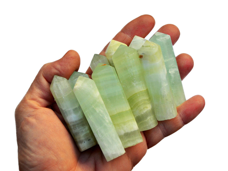 Some green pistachio calcite crystal points 50mm-55mm on hand with white background