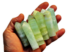 Hand holding pistachio calcite crystal points against a white background