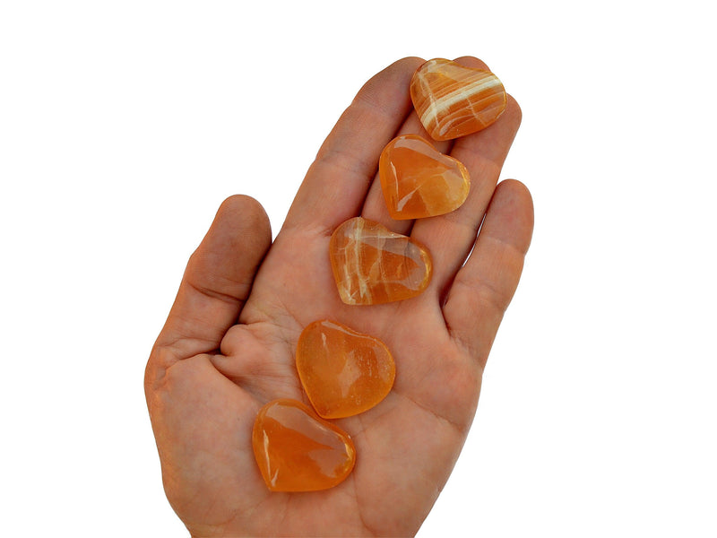 Five honey calcite crystal hearts small 25mm-30mm on hand with white background