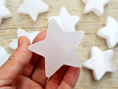 One pink mangano calcite stars 60mm on hand with background with some star stones on wood table