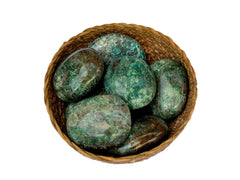 Several green chrysocolla palm stones inside a straw basket on white background